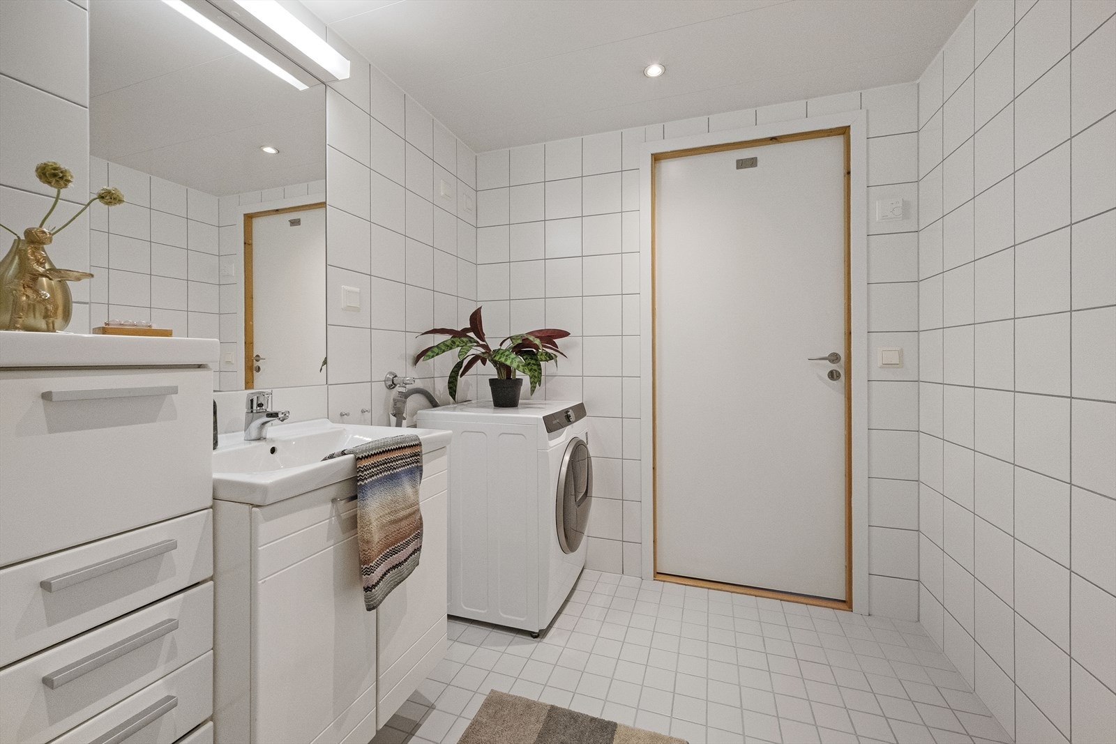 Badet er praktisk innredet som et kombinert baderom og vaskerom, med opplegg for vaskemaskin. Galleribilde