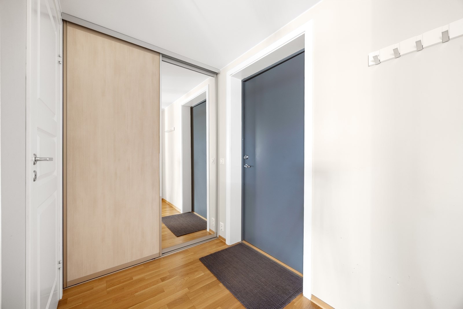 Med adkomst fra overbygget svalgang kommer man inn i leilighetens lyse gangarealer. Her er det god plass til sko- og klesoppbevaring i skyvedørsgarderobe med speilfelt. Galleribilde