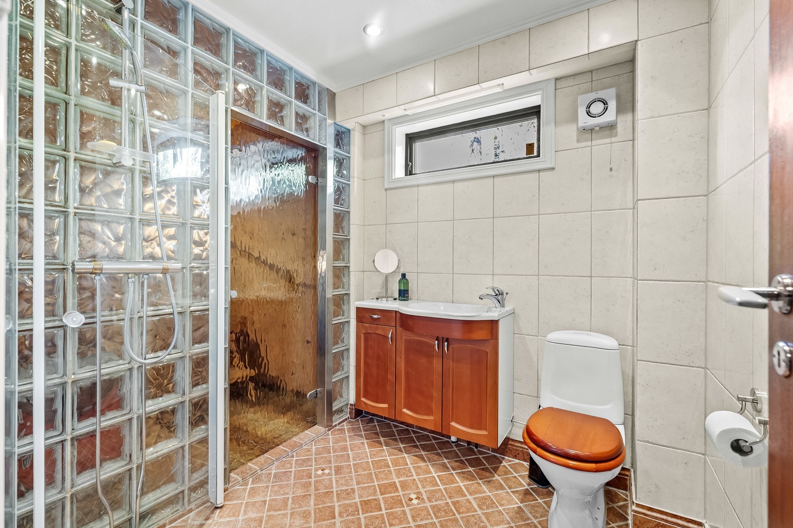 Bad med adkomst til badstue. Badet er innredet med stor servant med underskap, toalett og dusj med innfellbare dusjdører. Galleribilde