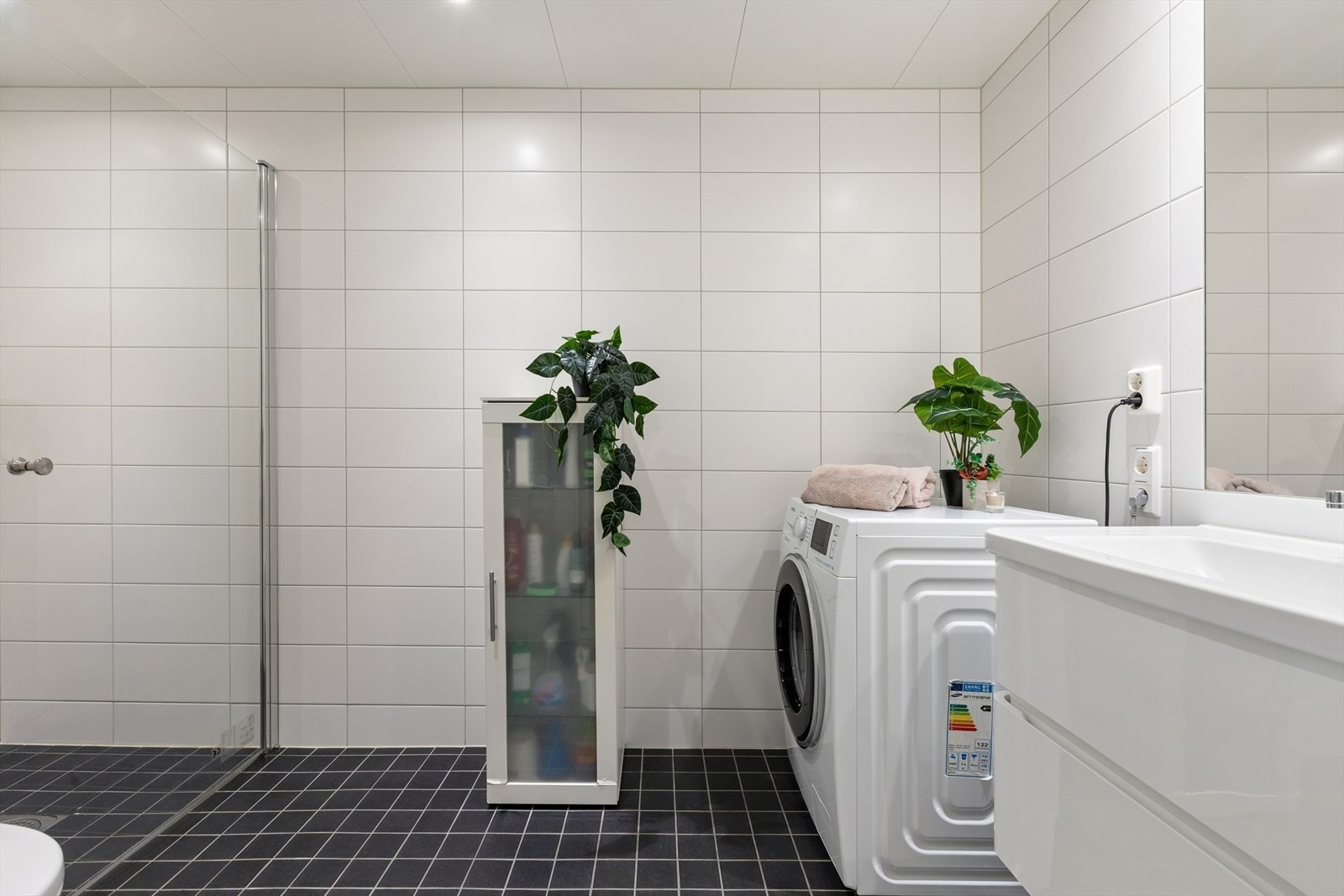 Badet er innredet med stilren baderomsinnredning, dusjnisje med glassdør og vegghengt toalett. Galleribilde