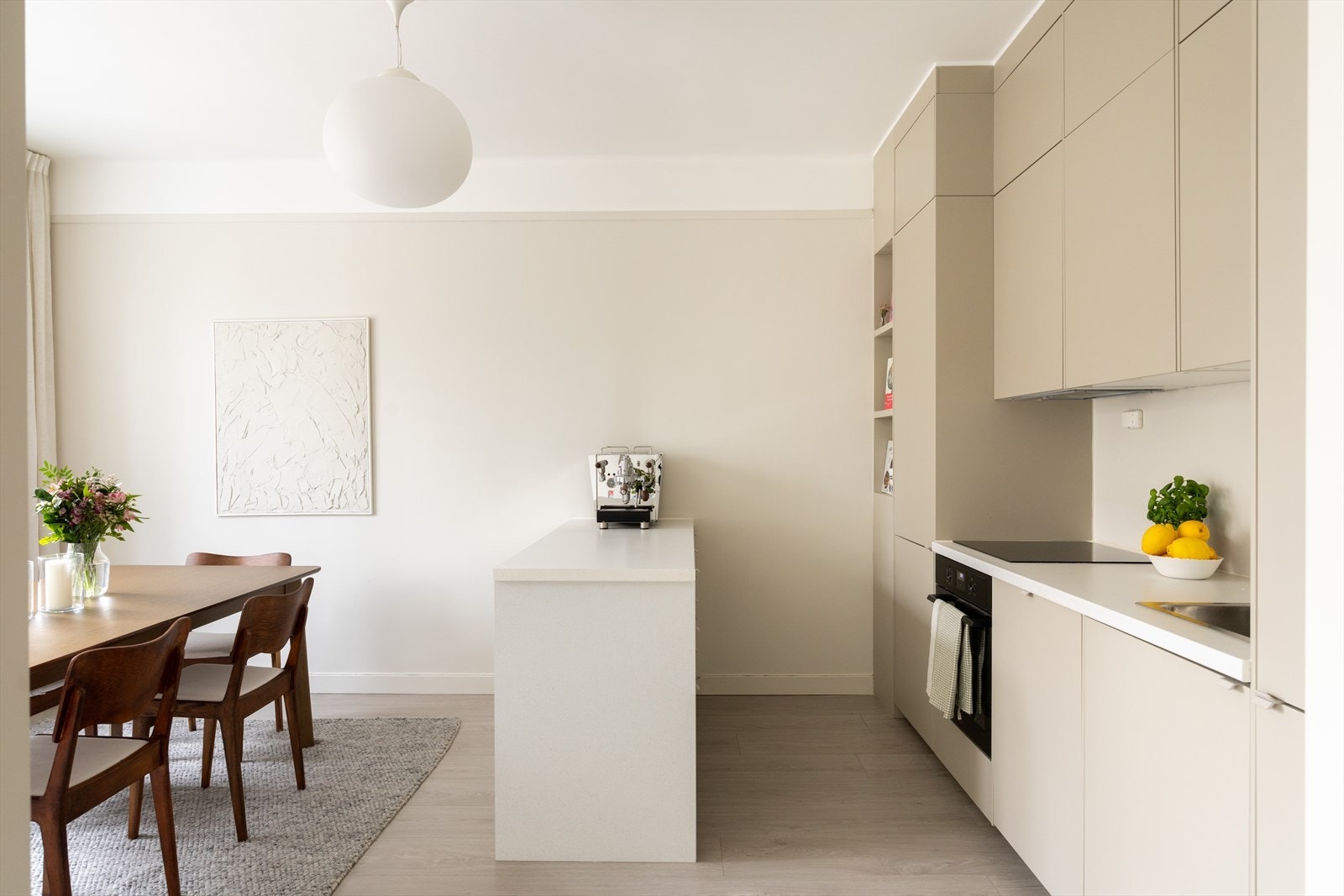 Tiltalende kjøkken hvor kjøkkeninnredningen består av beige glatte fronter og benkeplate av laminat med nedfelt vask. Galleribilde