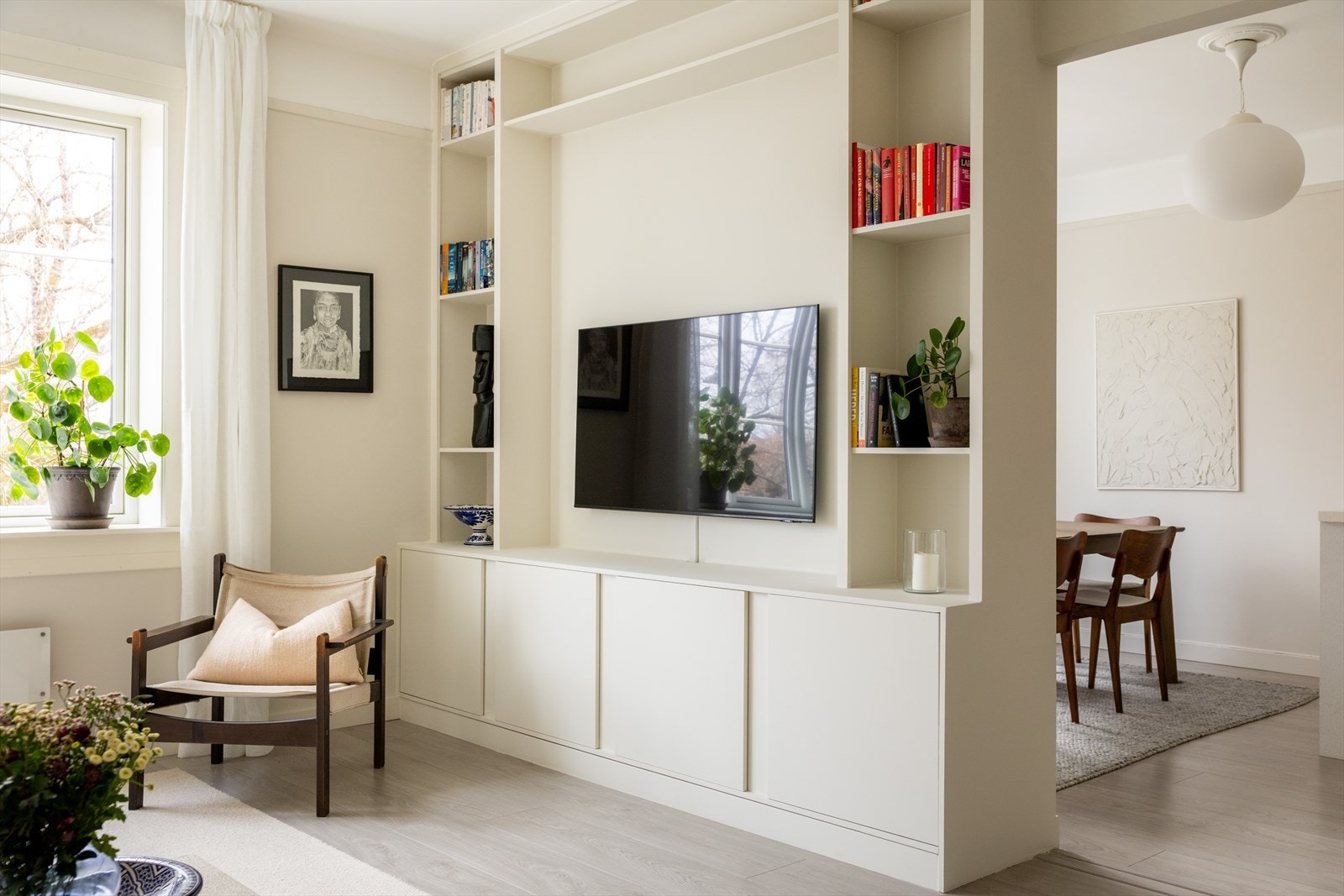 Den innbydende stuen kombinerer moderne stil med funksjonelle løsninger, der plassbygde hyller og skap gir både eksklusivt preg og gode oppbevaringsmuligheter. Galleribilde