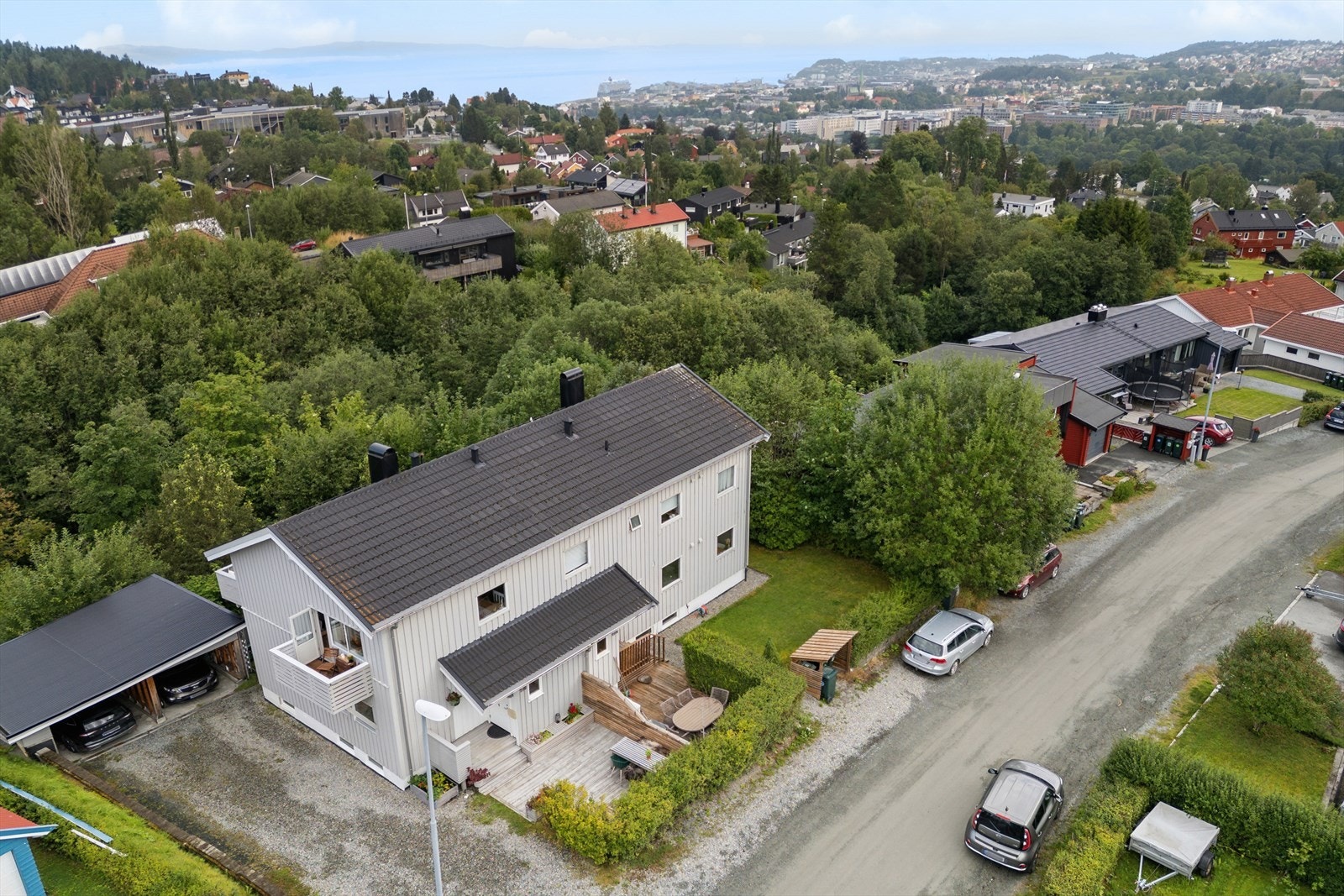Boligen ligger i en gate med begrenset trafikk, omkranset av grønne omgivelser. Galleribilde