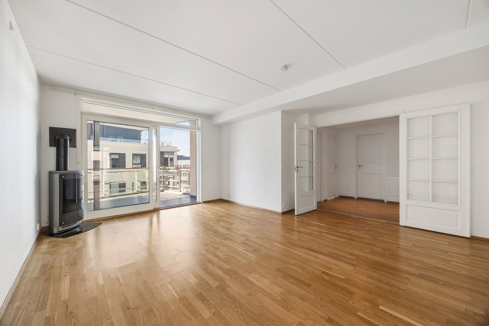 Stor og lys stue med utgang til balkong og gode lysforhold fra brede vindusflater. Rommet har fleksible møbleringsmuligheter og naturlig inndeling mellom oppholds- og spiseplass. Gjennomgående parkett og lyse overflater gir et tidløst og delikat uttrykk. Galleribilde