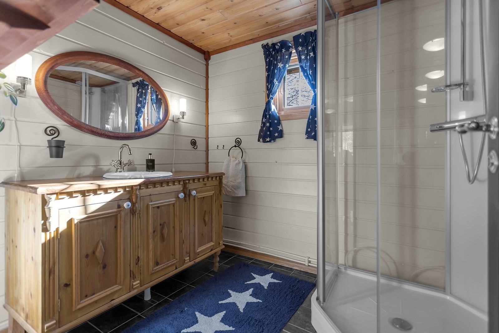 Badet har flislagt gulv med elektriske varmekabler, dusjkabinett og en romslig innredning med nedfelt servant. Galleribilde