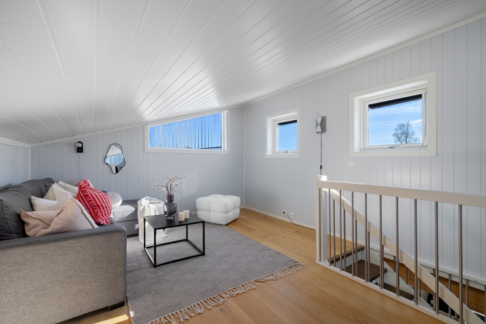 Lyst og romslig loftsrom med skråtak og tre vinduer som slipper inn naturlig lys. Galleribilde