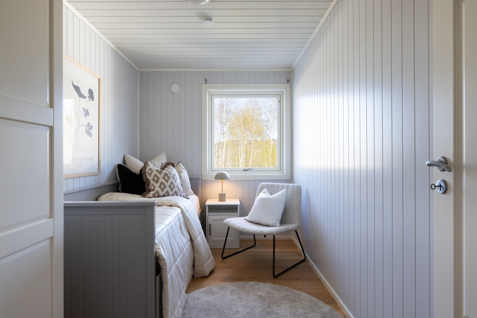 Lyst soverom med panelvegger og vindu som slipper inn naturlig lys. Galleribilde