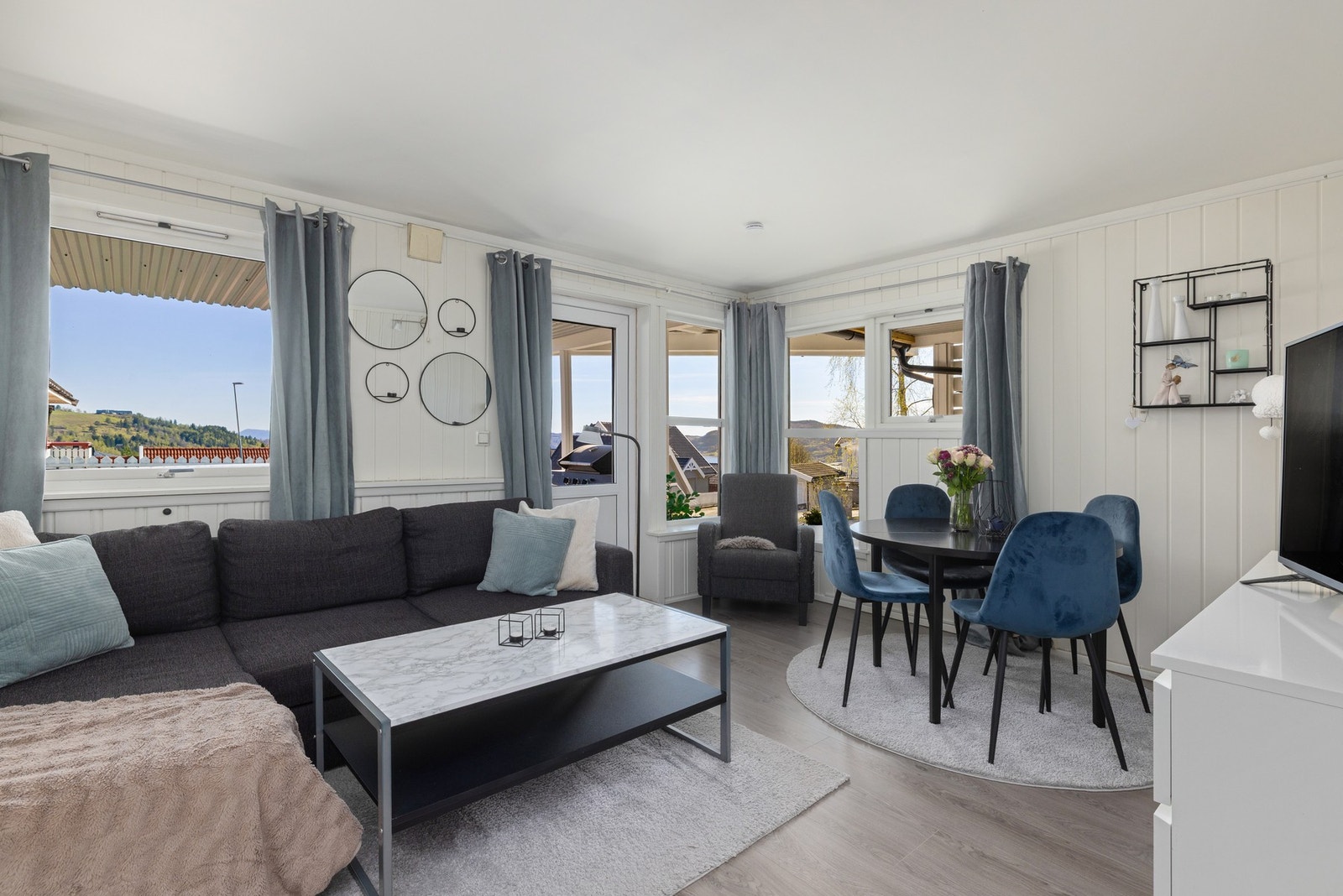 Lys stue med store vinduer, utgang til terrasse og utsikt over nærområdet. (utleie) Galleribilde