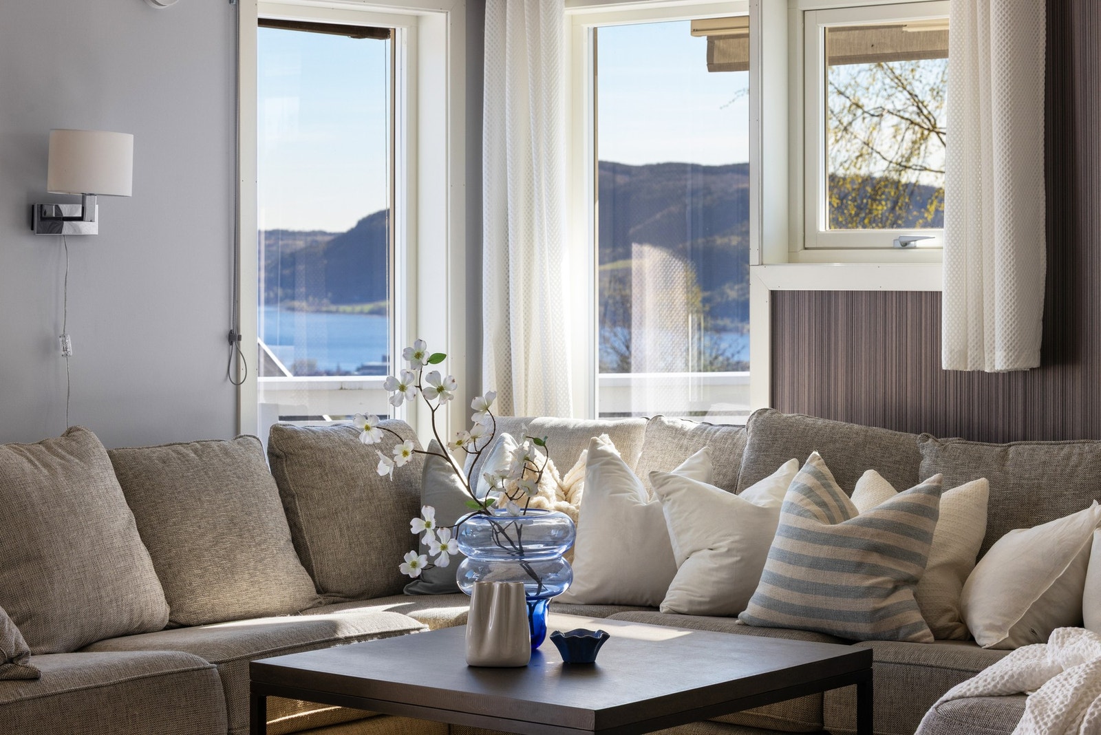 Lyst rom med store vinduer og flott utsikt mot sjø og fjell. Galleribilde