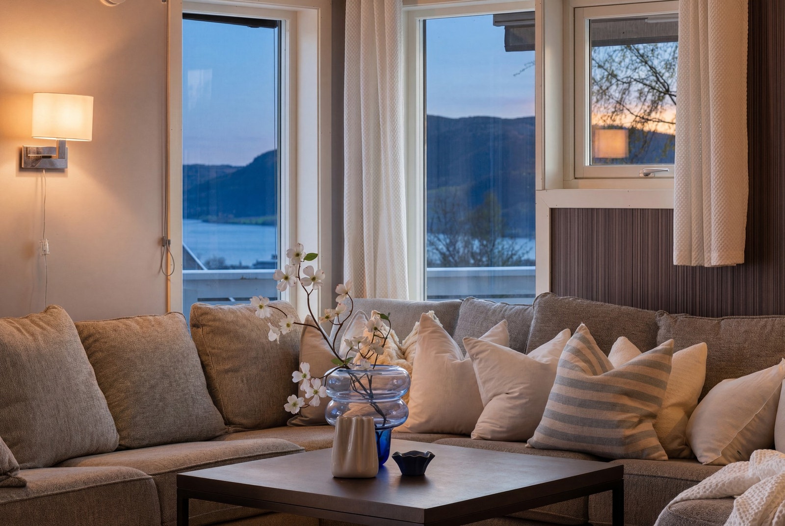 Store vinduer med utsikt mot fjorden og fjellene skaper en lys og innbydende atmosfære i denne delen av boligen. Galleribilde