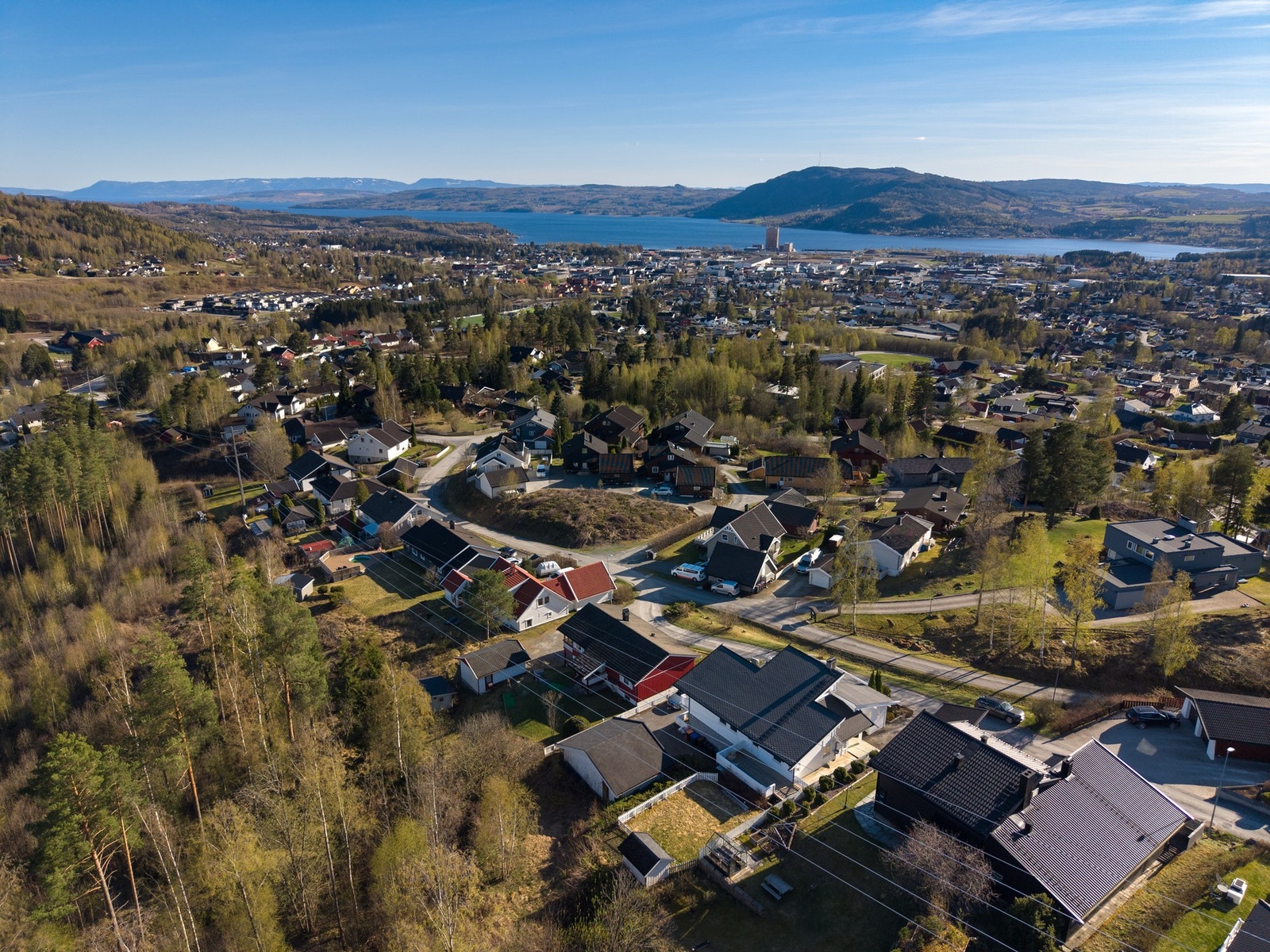 Luftfoto av et boligområde med utsikt over en innsjø og fjell i bakgrunnen. Galleribilde