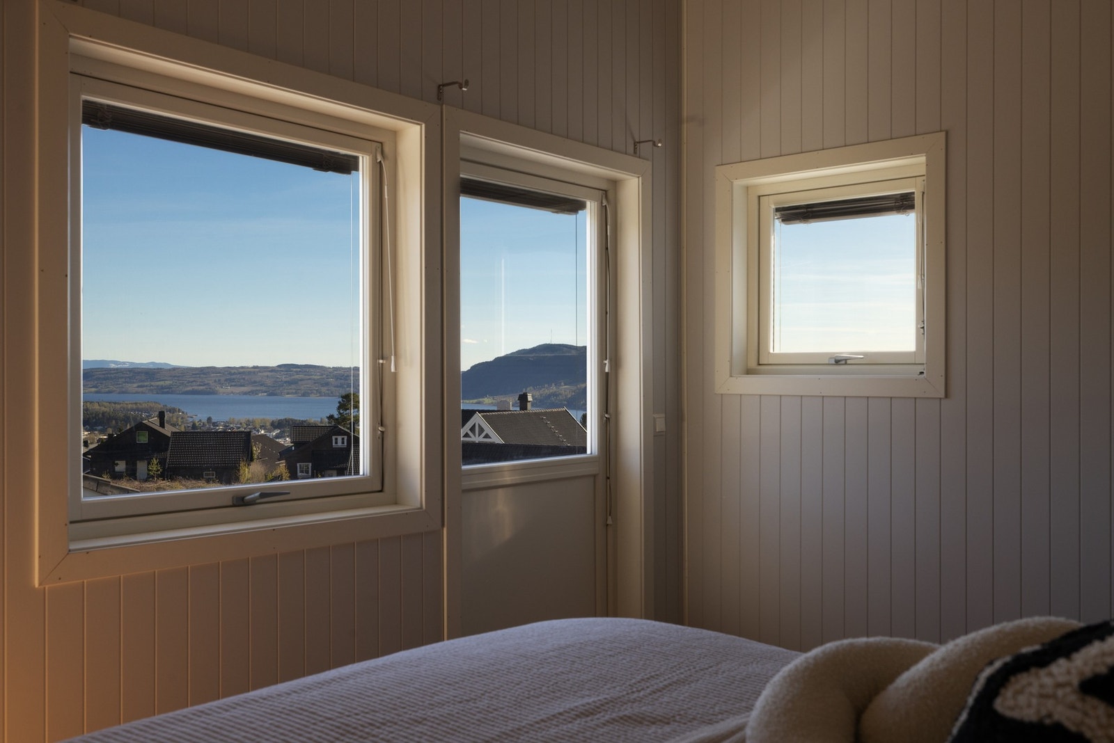 Rommet har store vinduer som gir utsikt over nærliggende hus og fjell i horisonten. Galleribilde