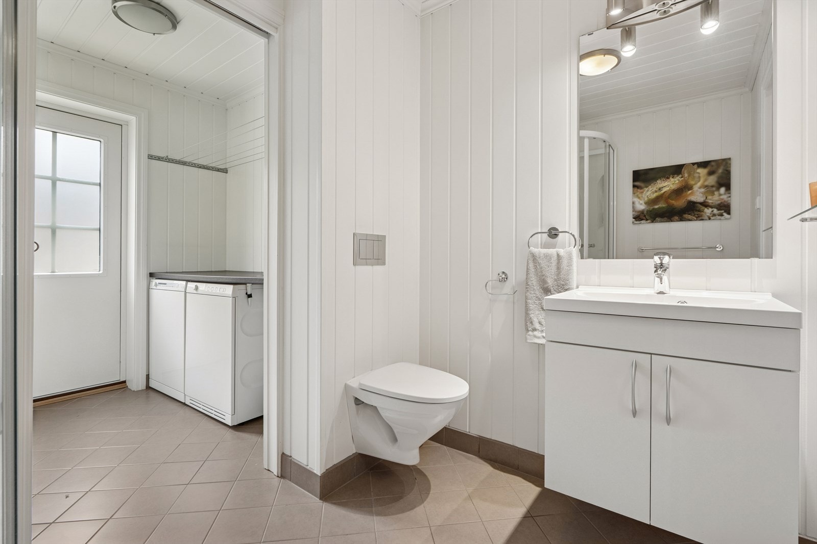 Badet er utstyrt med vegghengt toalett, dusjkabinett, samt baderomsinnredning med servant og blandebatteri. Galleribilde