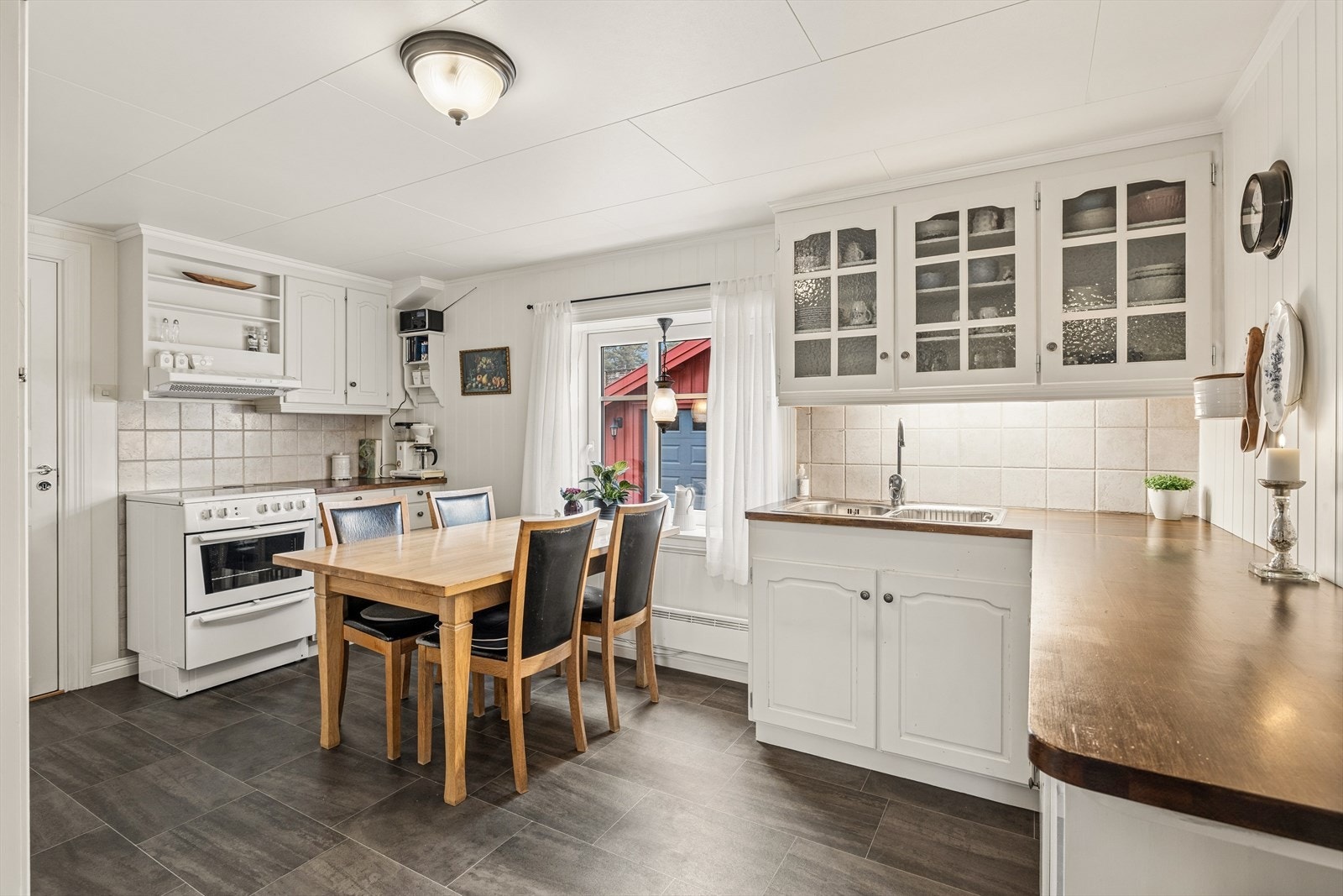 Kjøkkeninnredning med speilfronter og god plass til spisebord. Veggene har fliser mellom over- og underskap. Galleribilde