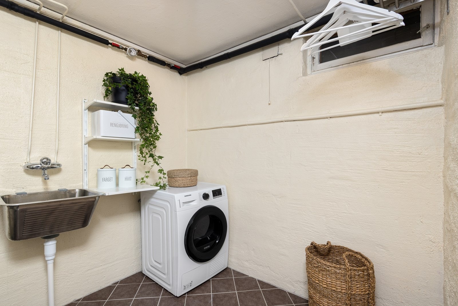 Praktisk vaskerom i kjelleren med fliser på gulv, skyllekar og opplegg for vaskemaskin. Galleribilde