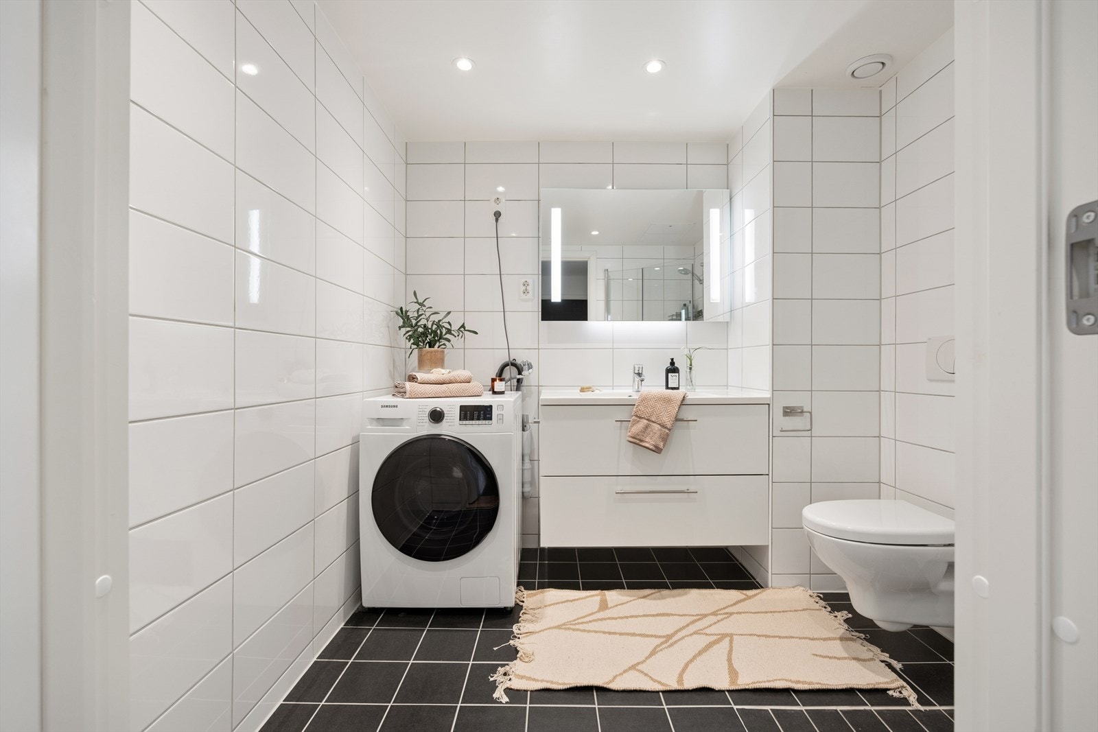 Moderne og helfliset bad med lekker innredning og opplegg for vaskemaskin. Galleribilde