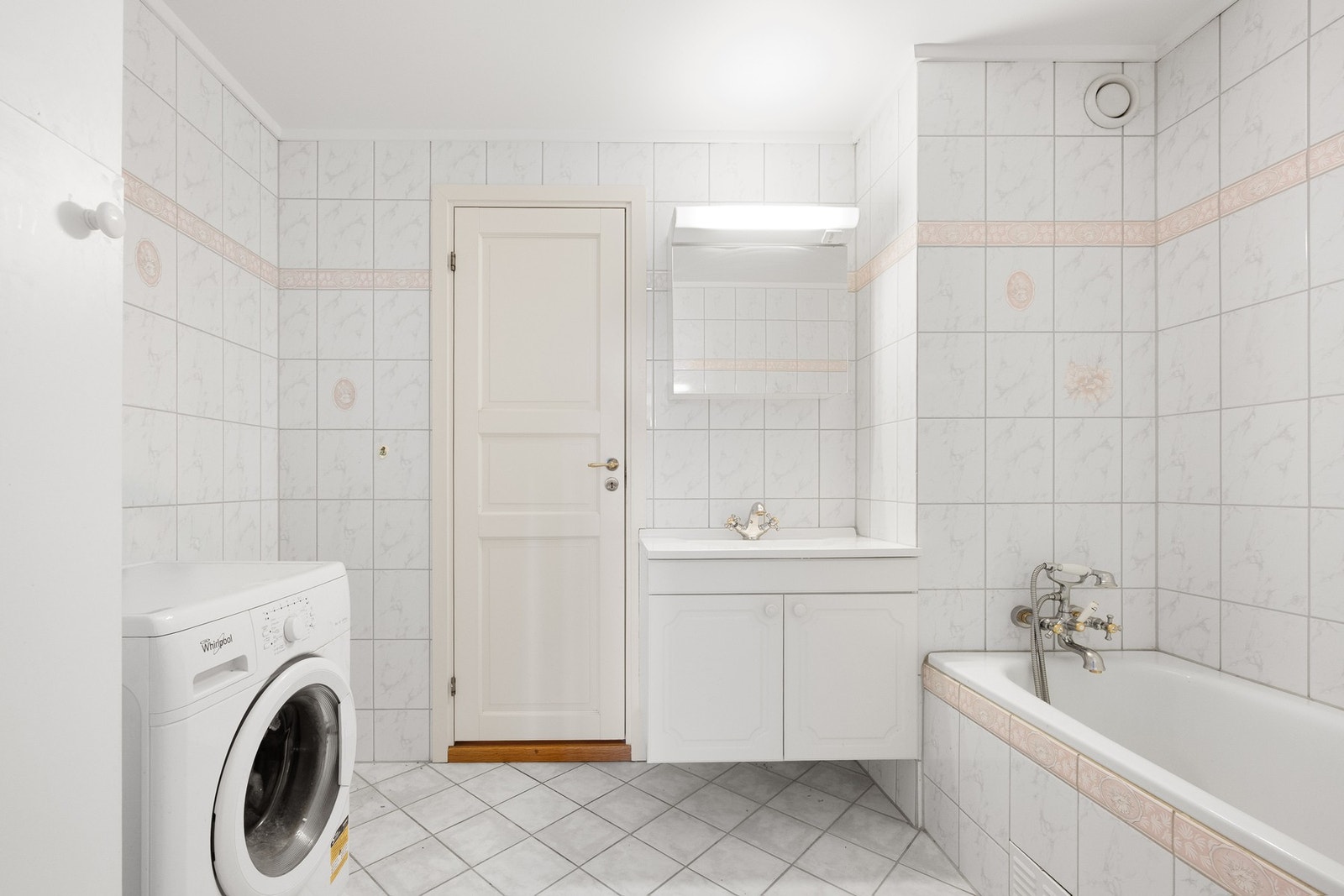 Romslig flislagt baderom med badekar og servant. Galleribilde