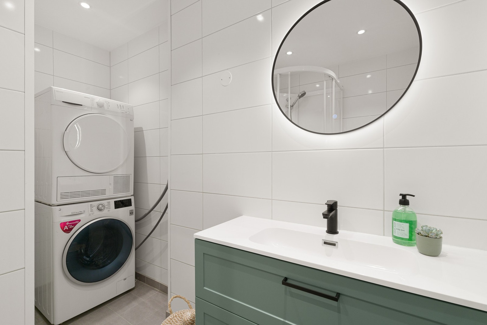 Badet er helfliset og fremstår moderne og funksjonelt. Det er utstyrt med dusjhjørne, vegghengt toalett og servantinnredning, samt et eget innhuk med opplegg for vaskemaskin og tørketrommel Galleribilde