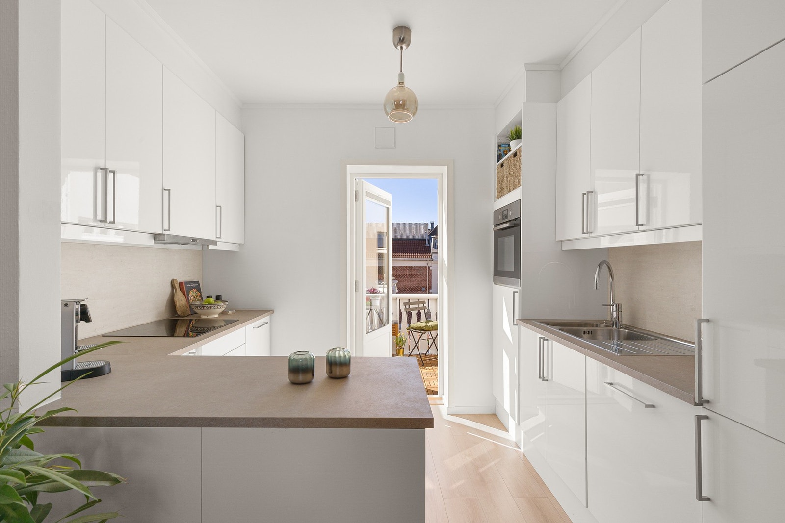 Kjøkkenet har en stilren innredning med glatte fronter og laminat benkeplate Galleribilde