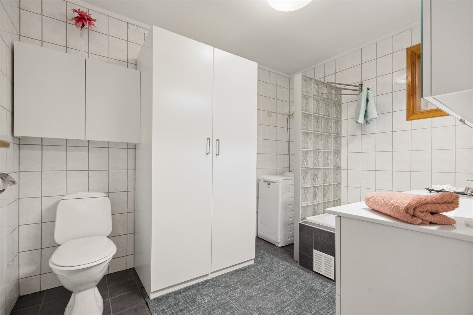 Romslig baderom på 5,5 kvm med flis på gulv og vegg, samt malt slett himling. Galleribilde