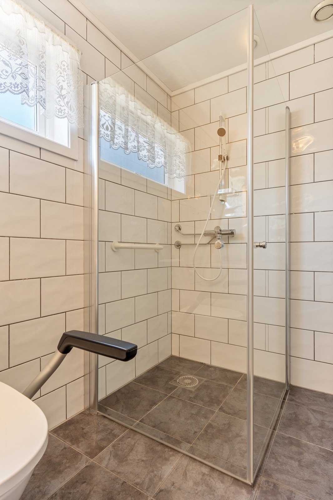 Badet/vaskerommet inneholder dusjhjørne, toalett, innredning med servant, varmtvannsbereder og opplegg for vaskemaskin. Galleribilde