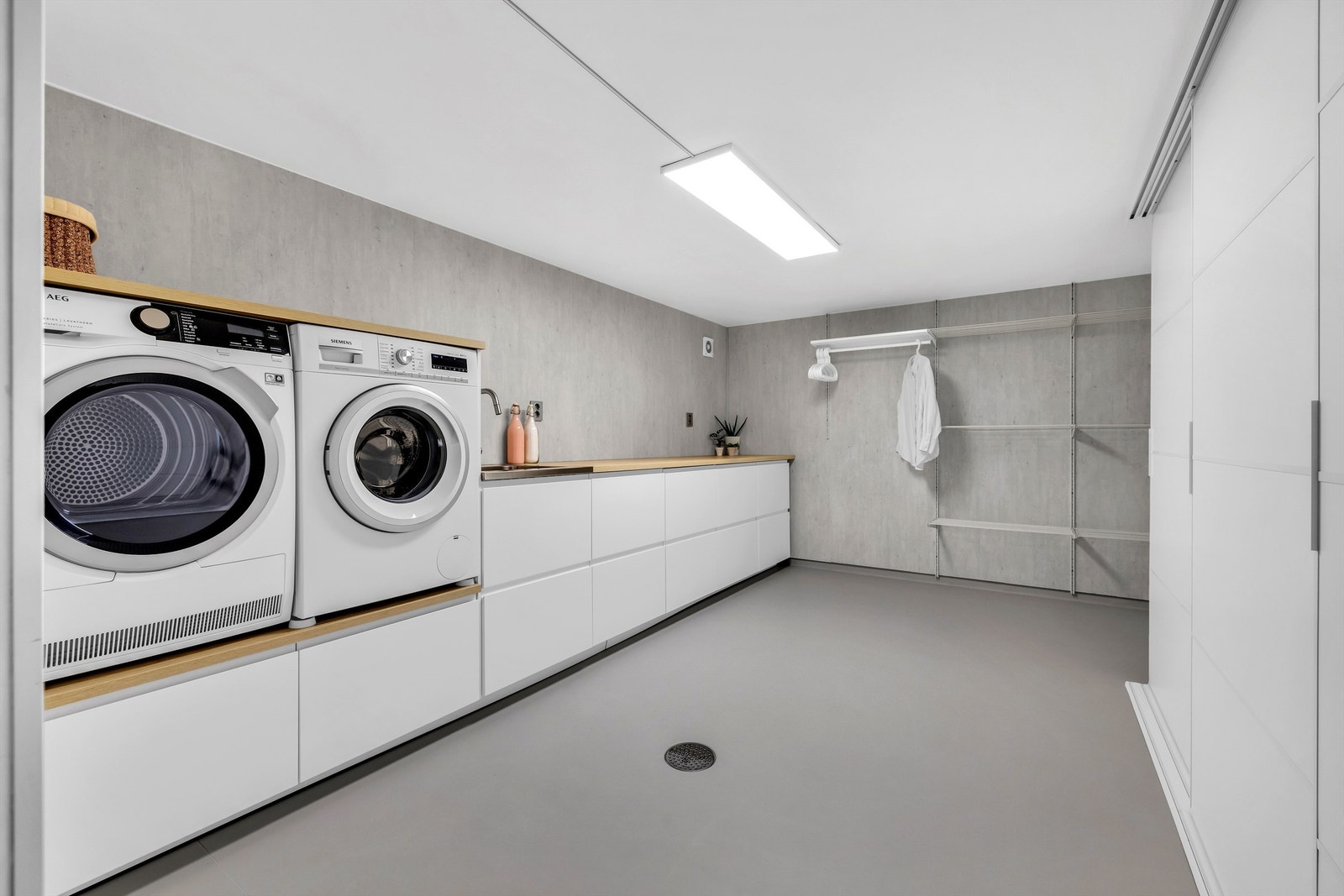 Vaskerommet er stort og nytt med varme i gulvet, gode lagringsmuligheter og tørking av klær i et smart oppheng på vegg. Innredningen på vaskerommet er fra Ikea og har glatte fronter, laminat benkeplate og skyvedørsgarderobe med glatte fronter. Galleribilde