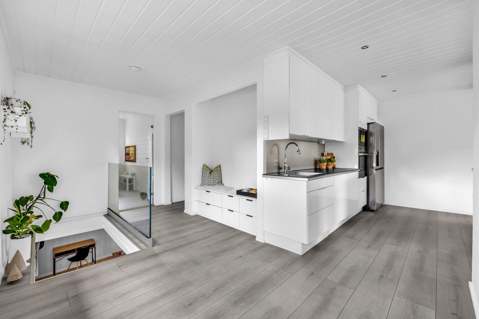 Kjøkkenet er utstyrt med integrerte hvitevarer som oppvaskmaskin, komfyr og mikrobølgeovn plassert i høyskap, samt et frittstående kjøleskap, noe som bidrar til et sømløst design. Galleribilde