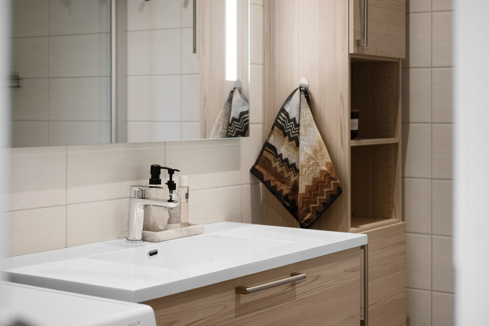 Badet er innredet med moderne servantskap, vegghengt toalett med innebygd sisterne og dusj med skjermvegger i herdet glass Galleribilde