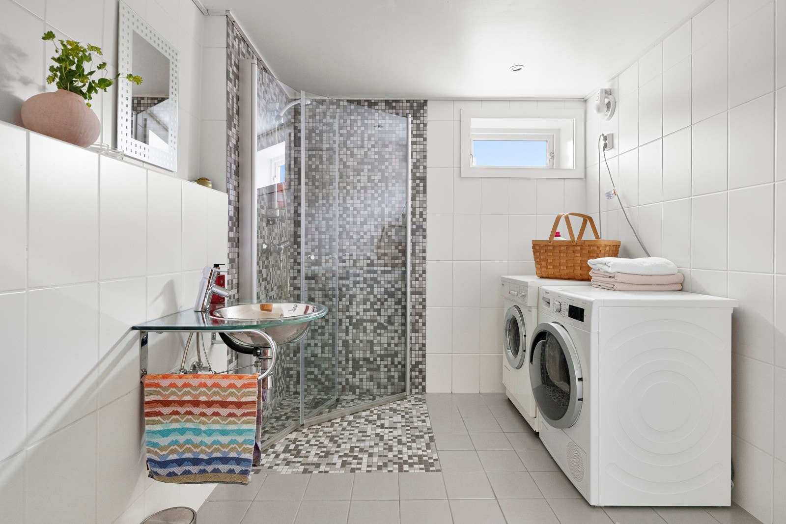 Badet i underetasjen er et funksjonelt rom som i dag benyttes som kombinert bad og vaskerom. Rommet har en praktisk utforming som dekker daglige behov, med plass til både vaskemaskin og øvrig utstyr. Galleribilde