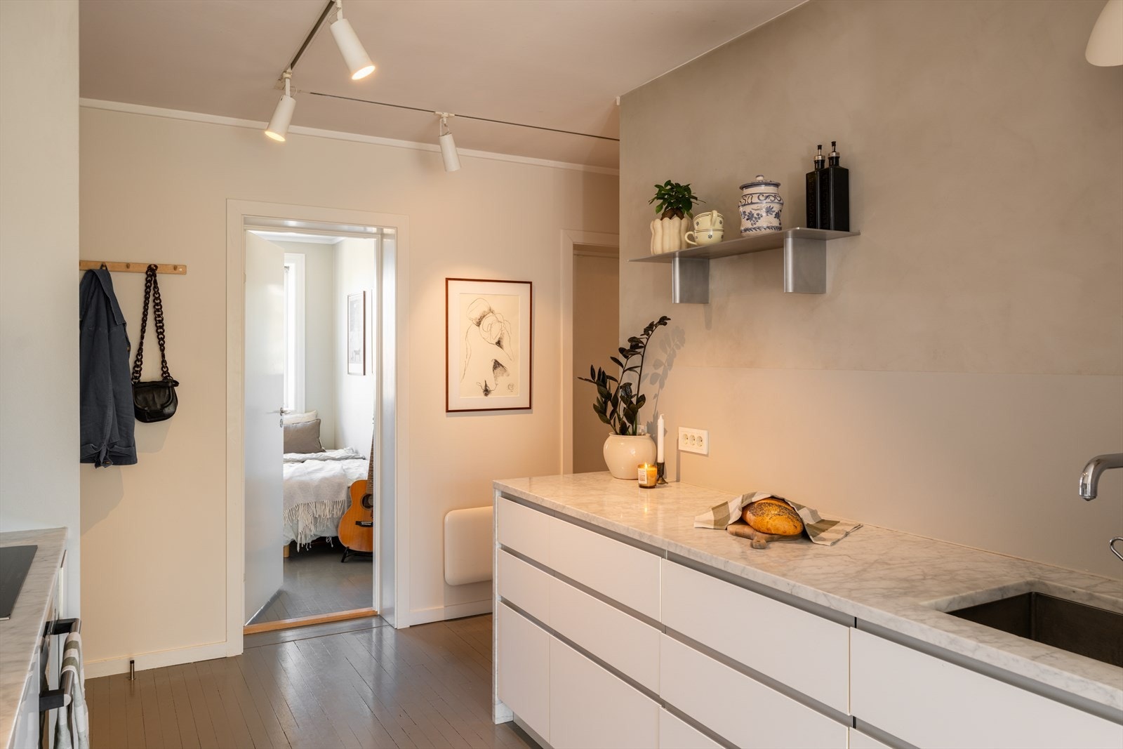 Kjøkkenet har en solid benkeplate i stein og en smart plassering som åpner opp mot leilighetens sosiale soner. Galleribilde