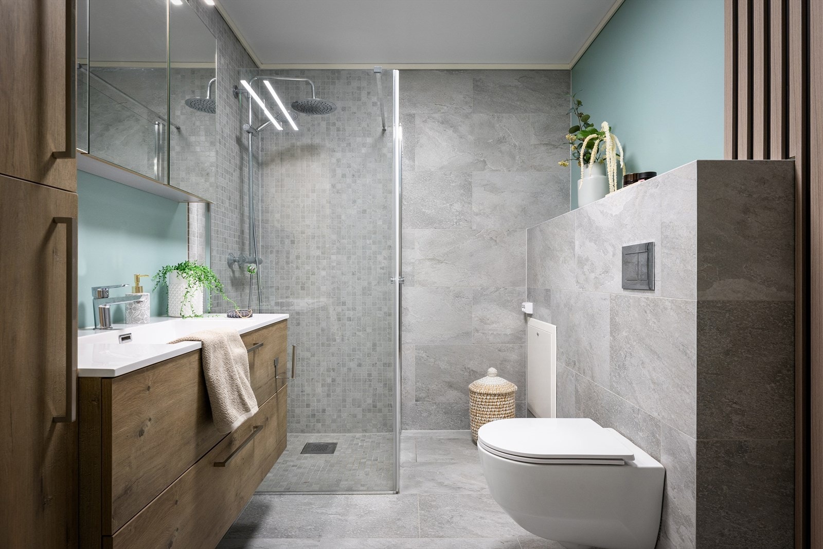 Badet er lekkert med grå fliser, vegghengt toalett, regndusj og dusjvegg i klart glass. Nytt i 2025. Pen innredning med speilskap. Galleribilde