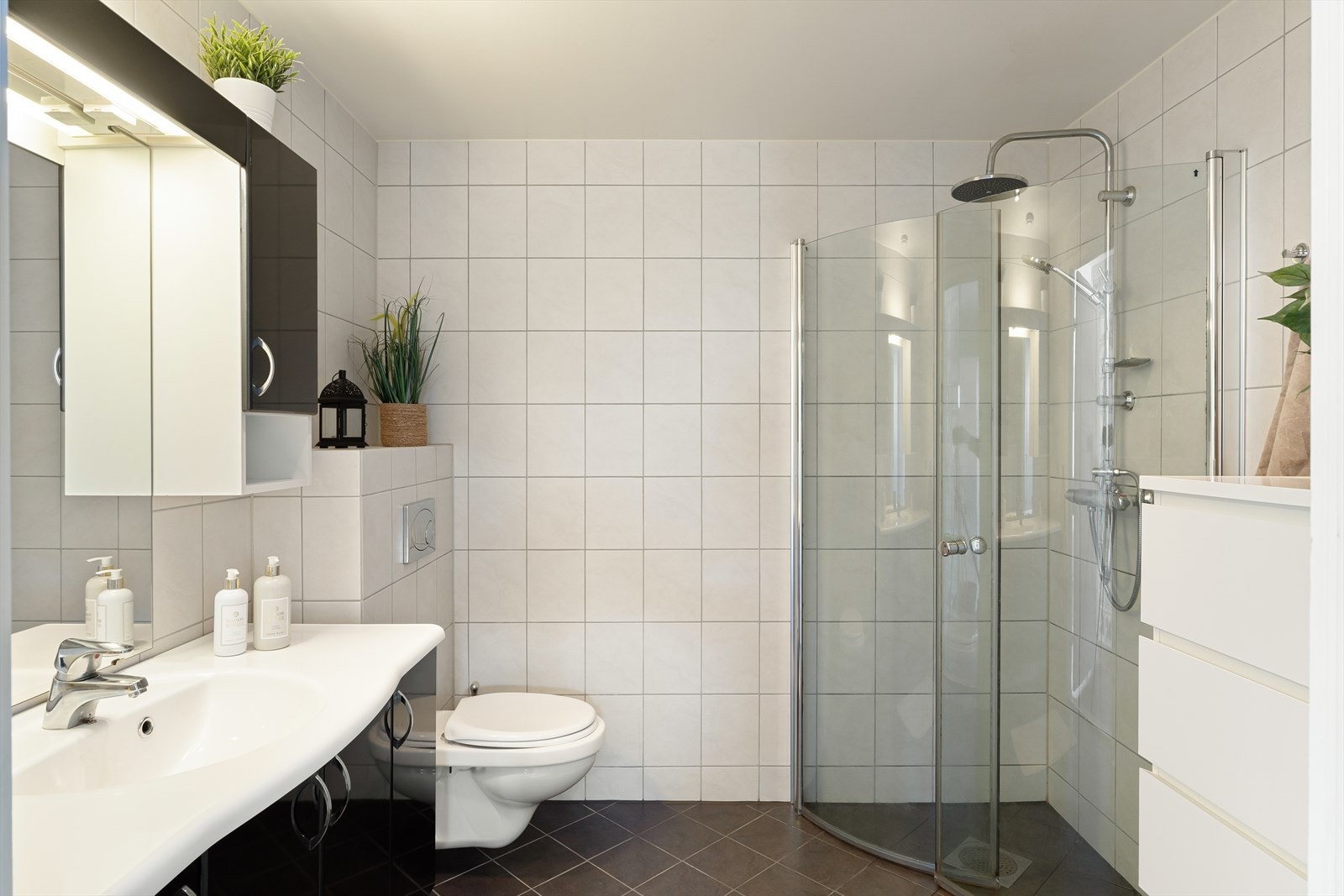 Badet fremstår som arealeffektivt med baderomsinnredning i svart utførelse. Galleribilde