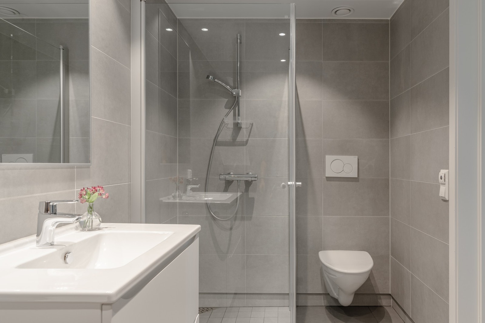 Badet inneholder dusj med glassdør, vegghengt toalett, opplegg for vaskemaskin og baderomsinnredning med gode oppbevaringsmuligheter. Galleribilde