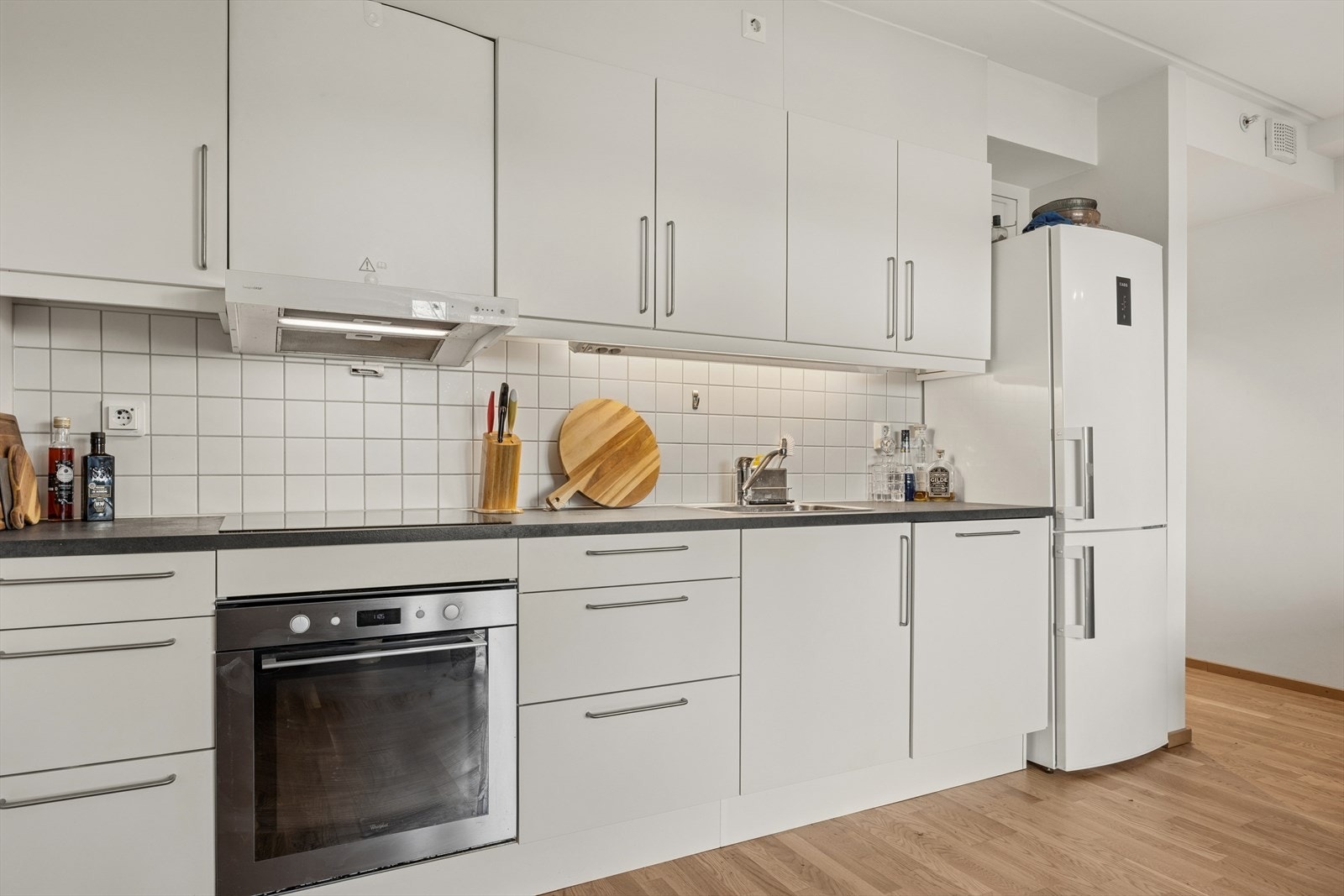 HTH kjøkkeninnredning fra 2017 har glatte, hvite fronter og en laminert benkeplate med oppvaskkum. Galleribilde