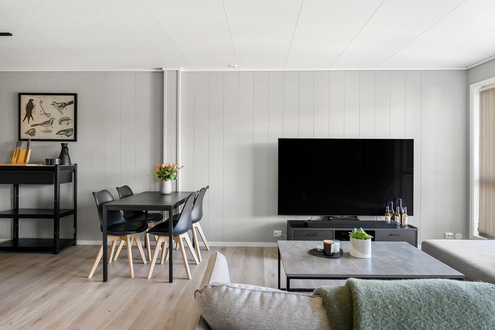 Gjennomgående laminatgulv og malte platevegger skaper et helhetlig inntrykk i stuen. Galleribilde