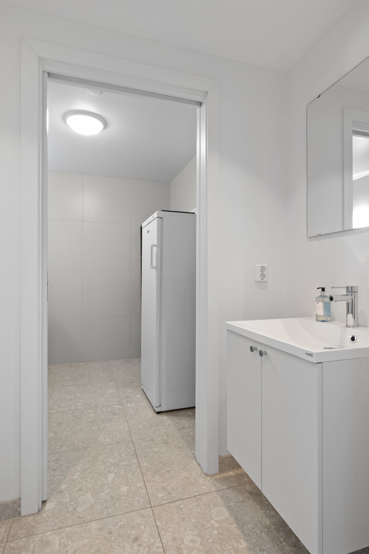 WC-rommet er utstyrt med gulvvarme, vegghengt toalett og et hvitt servantskap med tilhørende speil. Galleribilde