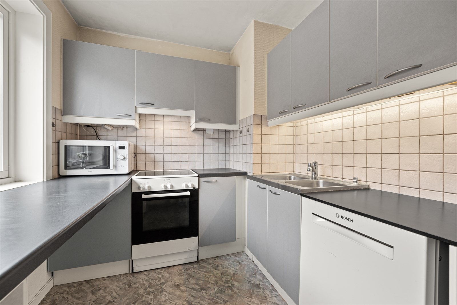 Kjøkkeninnredningen har glatte fronter, og både komfyr og oppvaskmaskin er på plass. Galleribilde