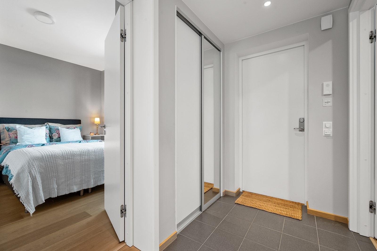 Praktisk inngangsparti som har flislagt gulv med gulvvarme og praktisk skyvedørsgarderobe med helspeil på en dør. Galleribilde