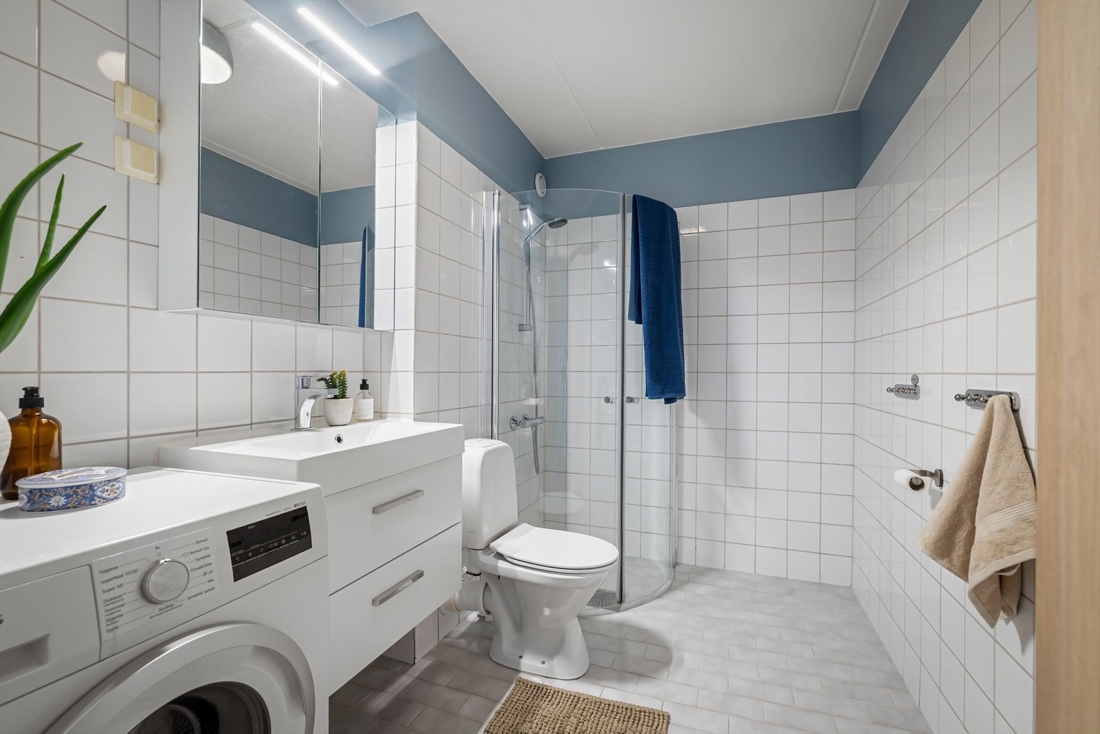 Badet er fra byggeår, men fremstår delikat med lyse fliser. Det er oppgradert innredning og speilskap med oppbevaringsplass. Galleribilde