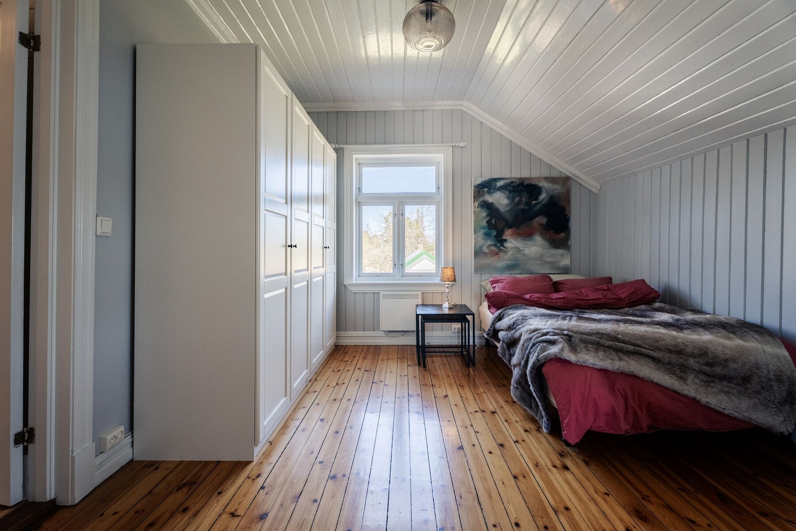 Soverom 2 har tilsvarende materialitet med furuplanker, hvitmalt panel og egne garderobeskap. Galleribilde