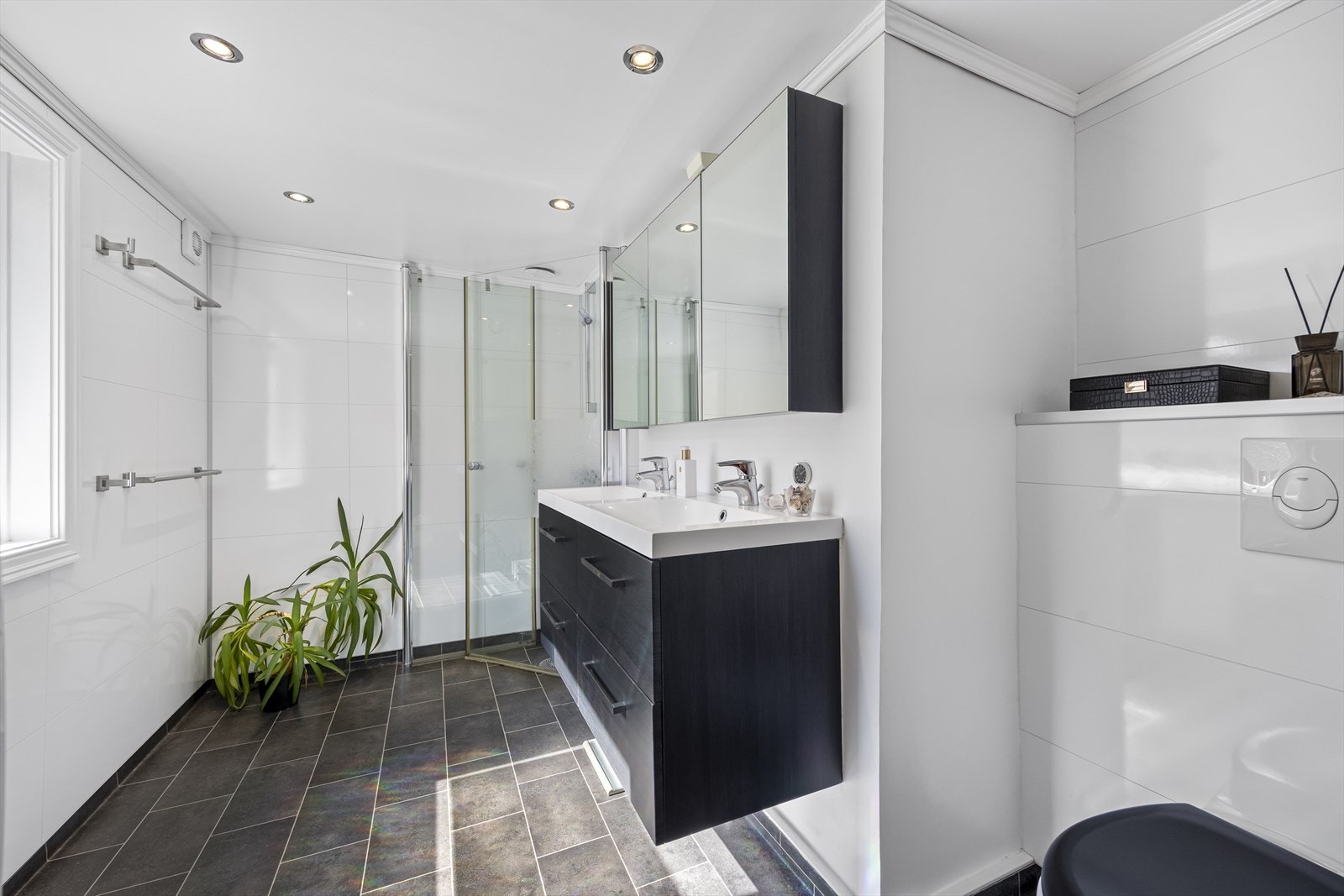 Badet ble totalrenovert i 2014 og har belegg på gulv med våtromsplater på vegg. Her er vegghengt toalett, dobbel servantinnredning med overskap samt dusjhjørne. Galleribilde