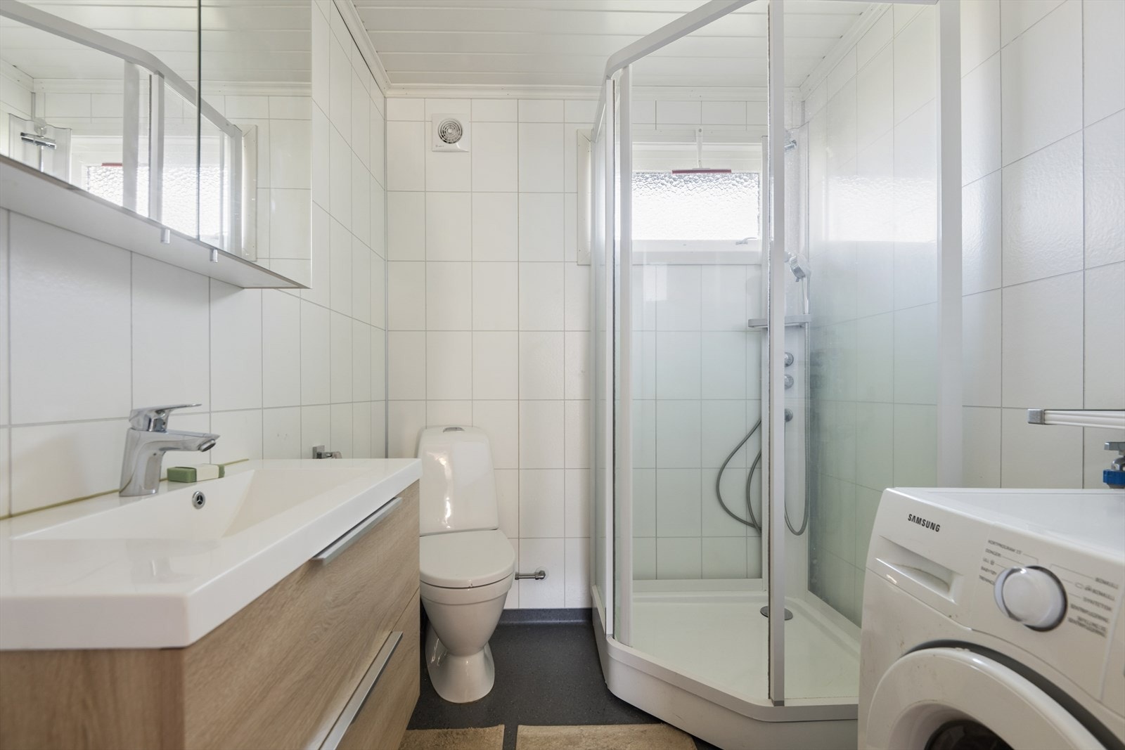 Badet er oppgradert etter 2020 med baderomsplater på veggene, dusjkabinett og opplegg for vaskemaskin. Galleribilde