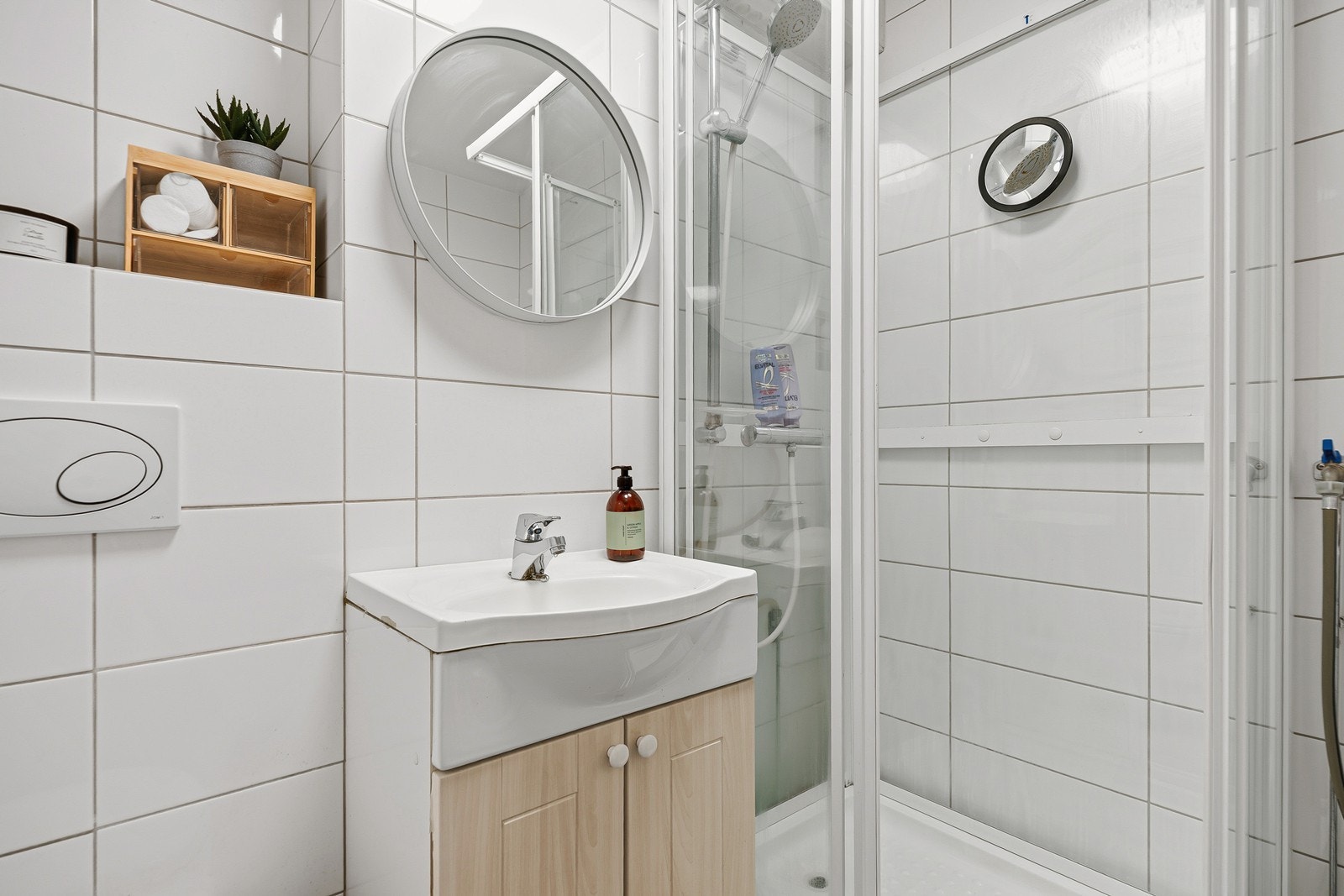 Badet er innredet med nedfelt servant, veggmontert toalett, dusjkabinett og opplegg for vaskemaskin Galleribilde