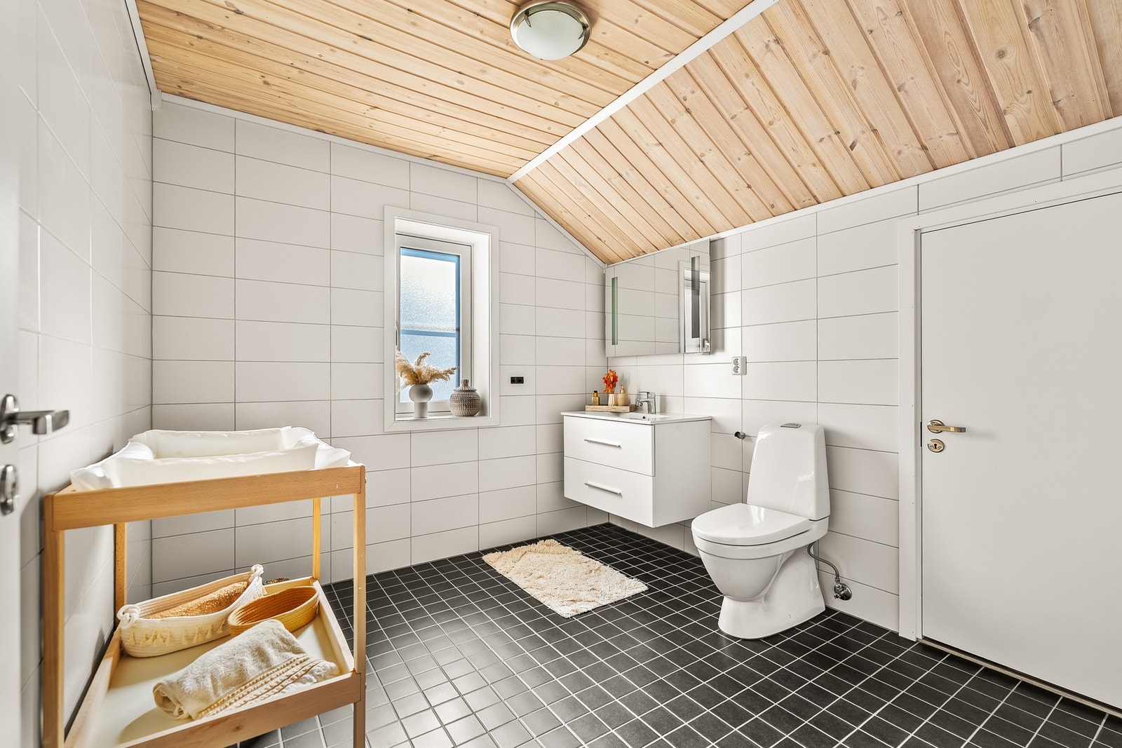 Badet i loftsetasjen er innredet med servant på benkeskap med glatte fronter, speil med belysning og gulvstående toalett. Dusjkabinett er ikke montert. Galleribilde