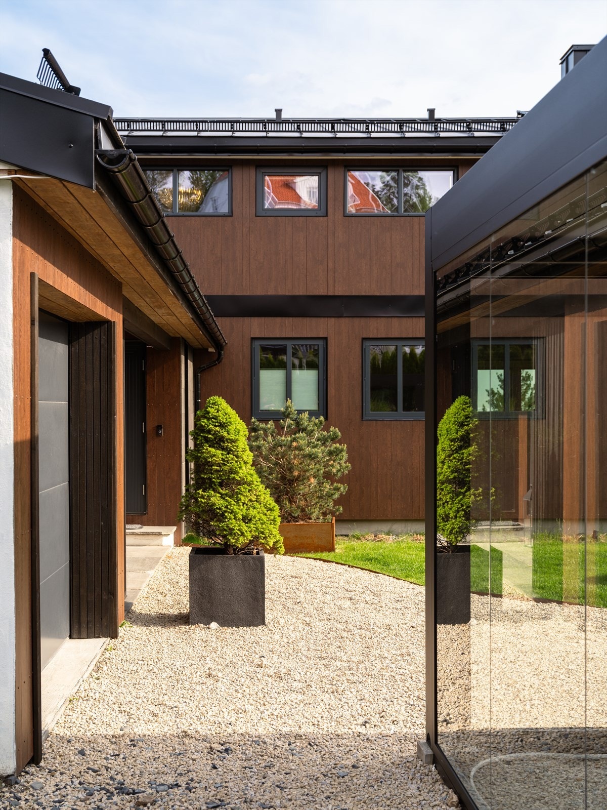 Tomten er pent opparbeidet med gressplen, beplantninger og gruset inngangsparti. Carport av glass. Galleribilde