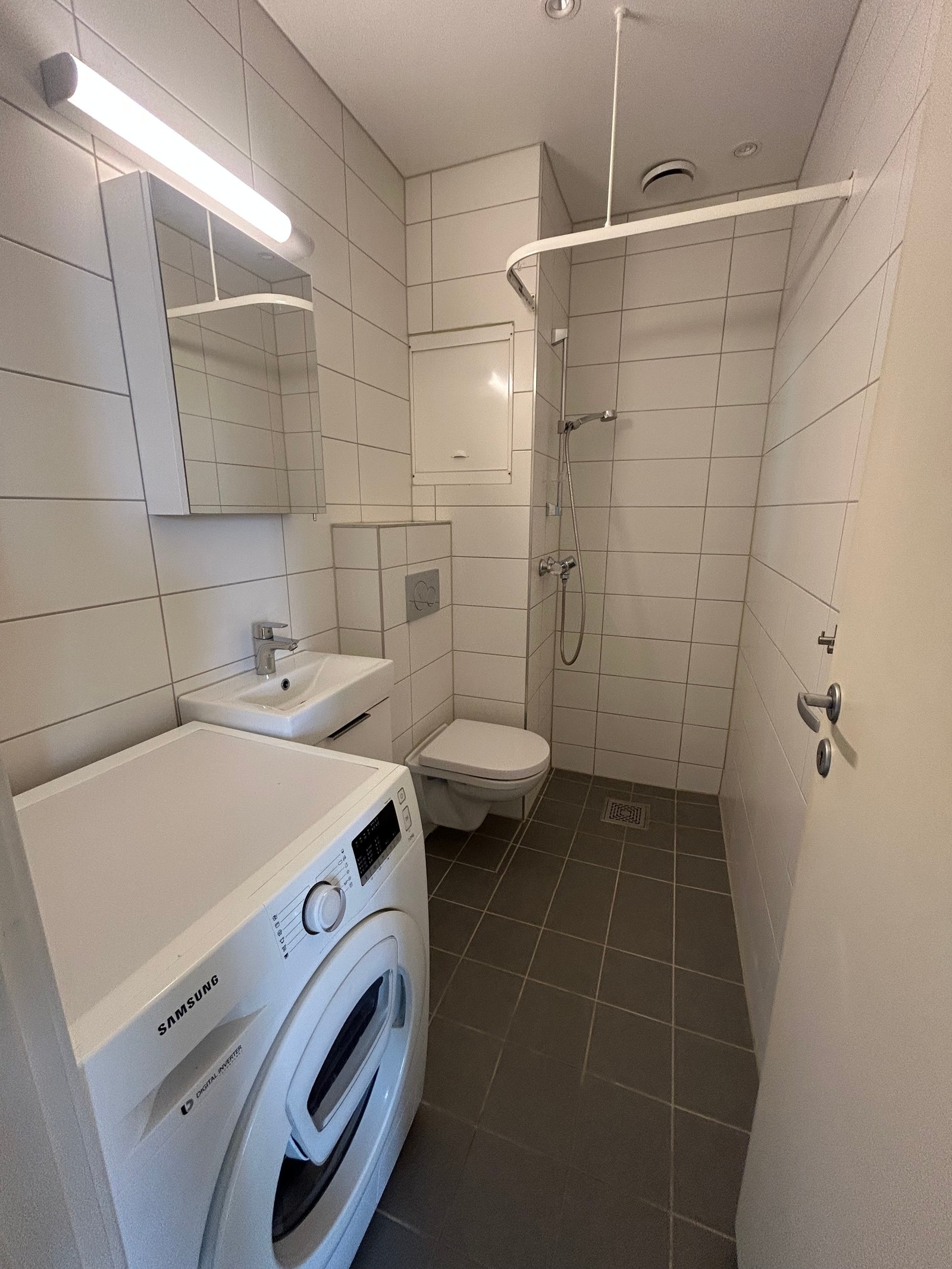 Flislagt dusjbad med varmekabler og vaskemaskin installert. Galleribilde