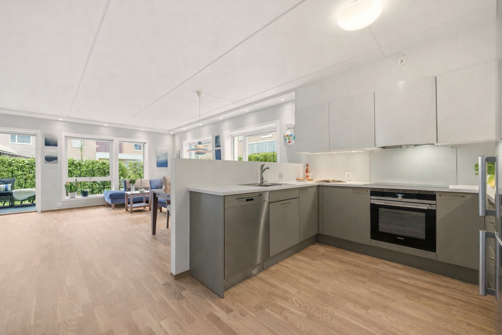 Kjøkkenet ligger i en åpen og sosial løsning - perfekt for sosiale sammenkomster. Bildet er kunstig sesongjustert med AI og er kun ment som illustrasjon. Galleribilde