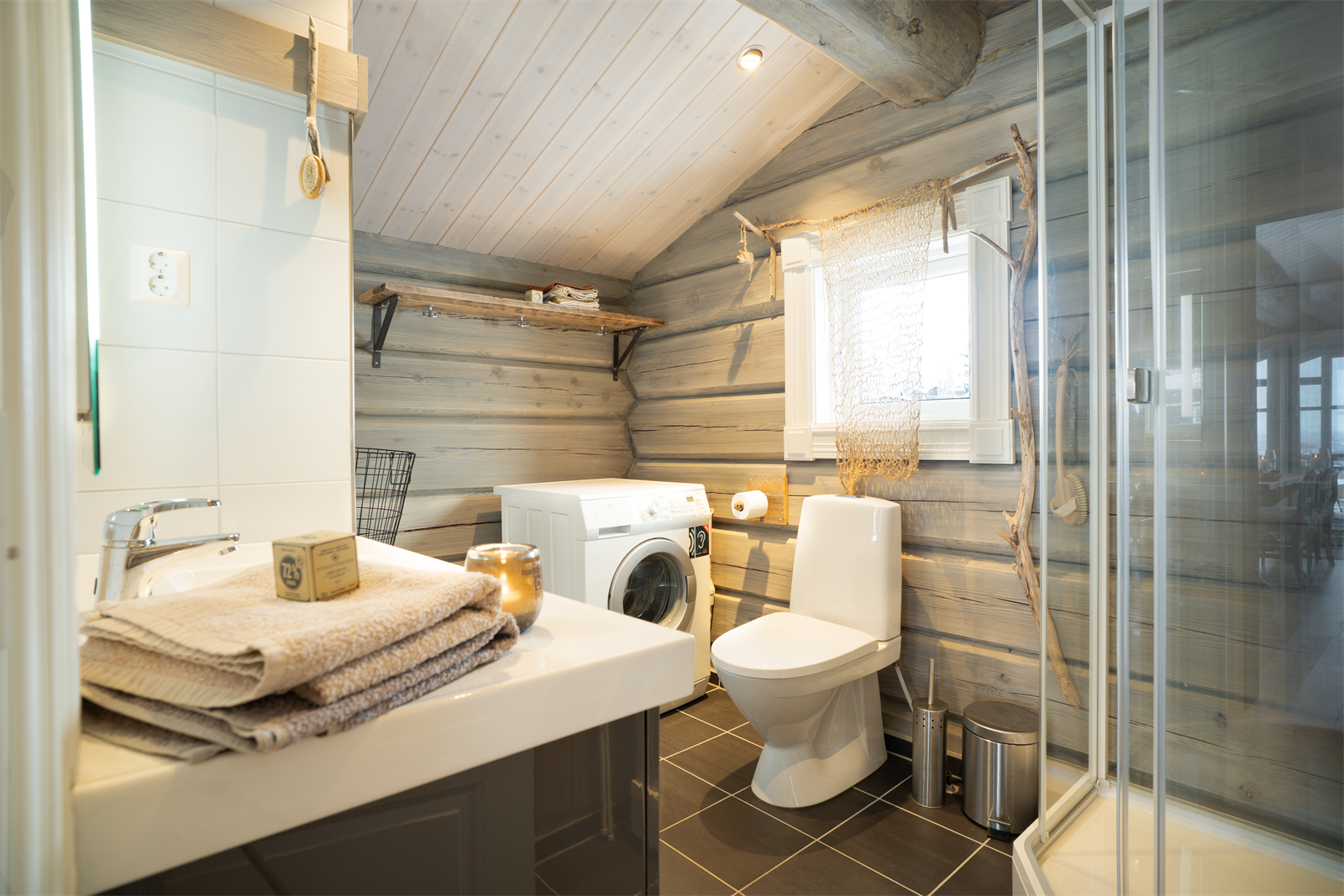Badet i andre etasje har flislagt gulv med gulvvarme, tømmervegger og opplegg for vaskemaskin. Galleribilde