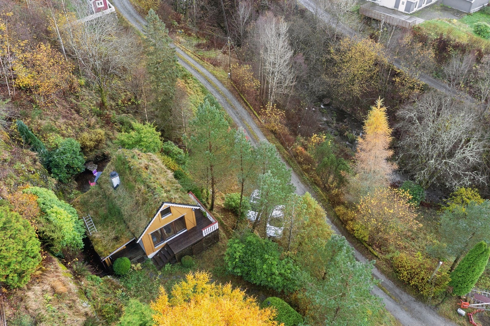 Fine uteområde rundt hytten m/ terrasser, plen, epletre, busker og annen beplantning. Tomten er skrånende med naturtomt på nedside av vei mot elv. Galleribilde