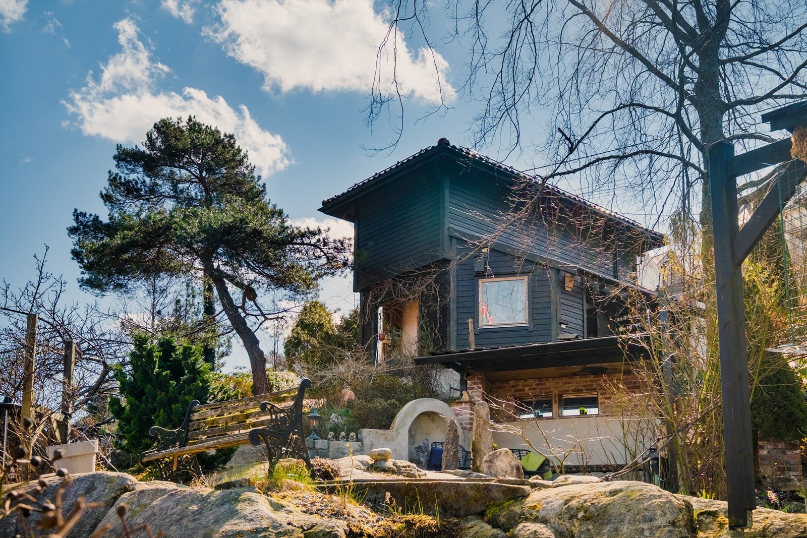 Huset er plassert i et skrånende terreng, noe som gir en dynamisk og spennende tomt. Her ser man opp på garasjen. Galleribilde